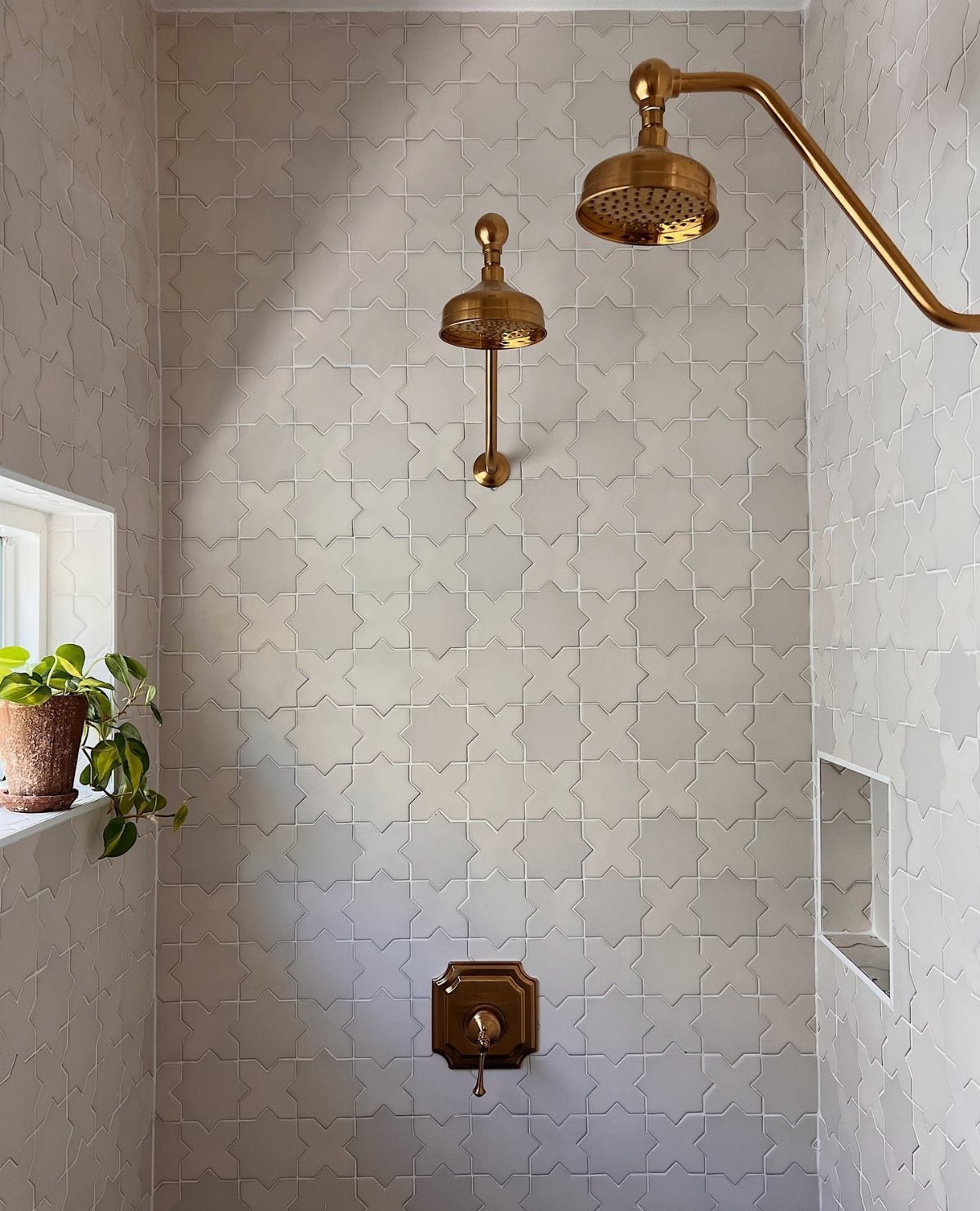 Bathroom Alcove Ideas: 29 Designs for Tubs, Showers & More 6 White star and cross ceramic tiles in a shower with gold fixtures.