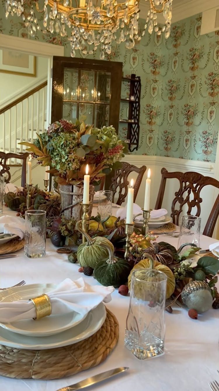 White tablecloth on a dining table with autumn pumpkins and floral centerpiece.