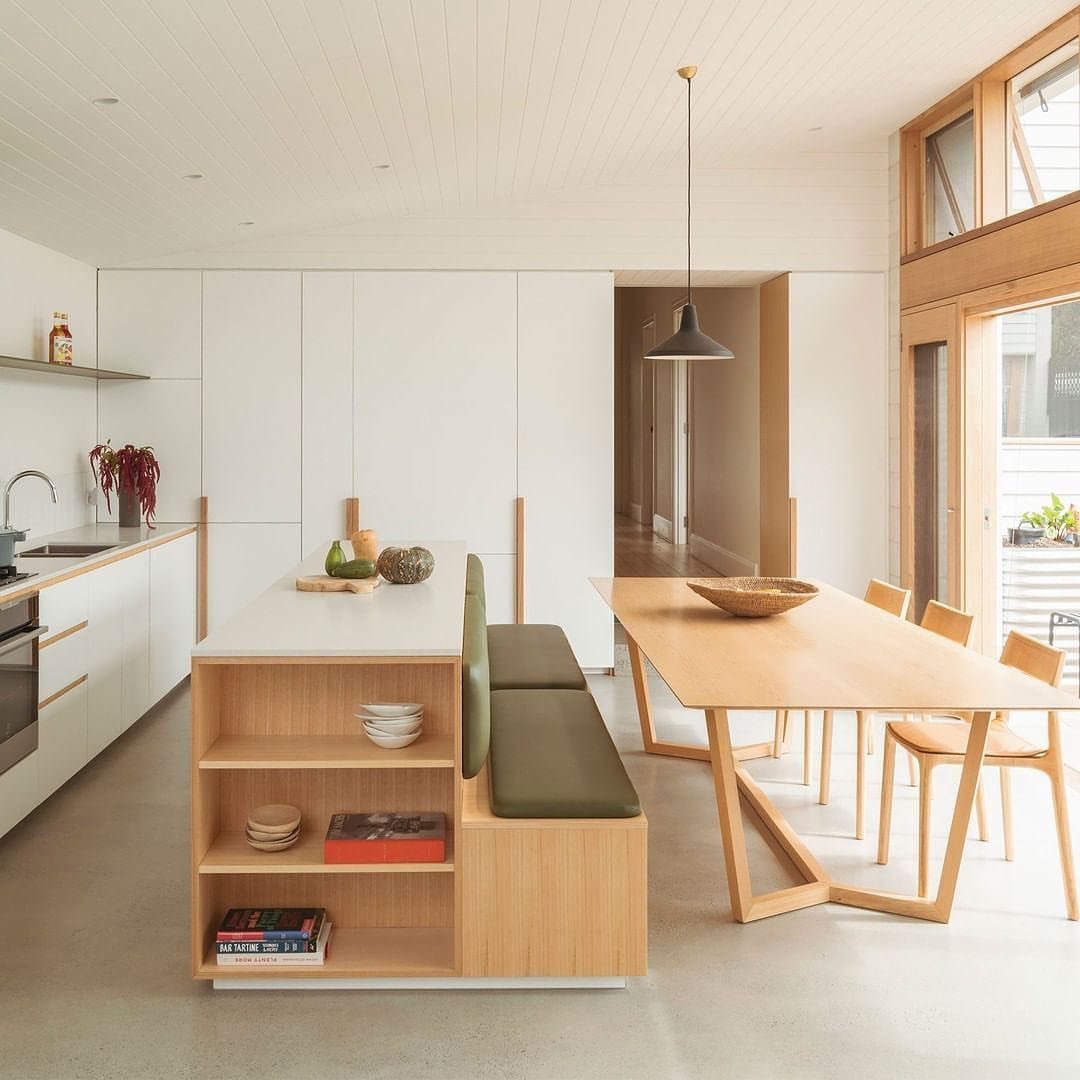 Modern kitchen and dining area with a built-in green bench and wooden table.