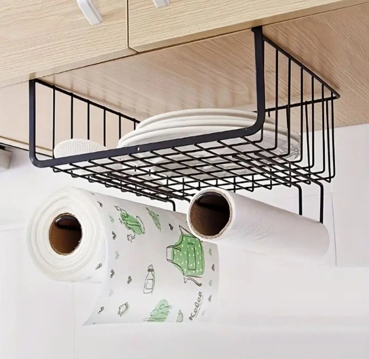 Black wire under-shelf basket holding white plates and paper towel rolls.