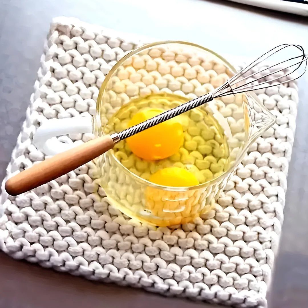 Small Kitchen Essentials: 13 Tools That Actually Matter 5 Metal whisk with wooden handle resting on a glass cup of raw eggs