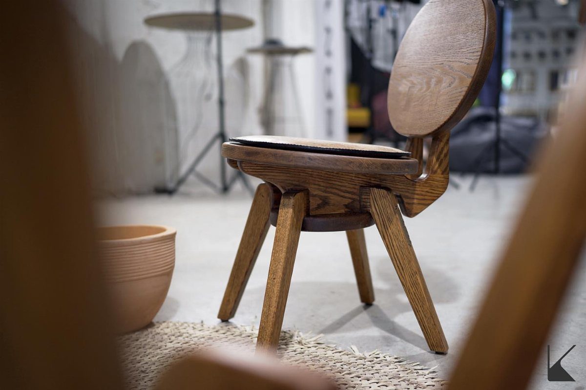Wood Art Furniture: 31 Ideas From Rustic to Sculptural Forms 9 Wooden chair with rounded backrest and dark cushion in a bright workshop setting.